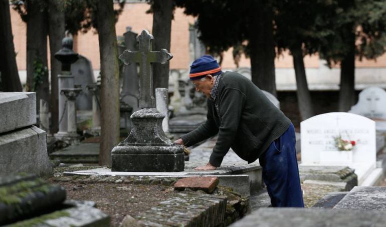 Un sepulturero limpiando una tumba del cementerio