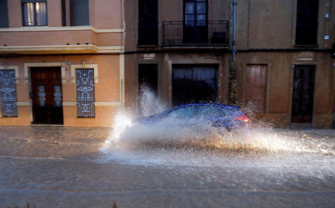 Un vehículo circula por una calle anegada de la ciudad de Valencia