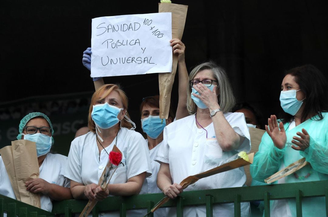 Personal médico del hospital 12 de Octubre de Madrid muestran pancartas en favor de la sanidad pública y aplauden durante un concierto brindado por la banda de la Policía Municipal en homenaje a los trabajadores sanitarios, este viernes en los exteriores del hospital.