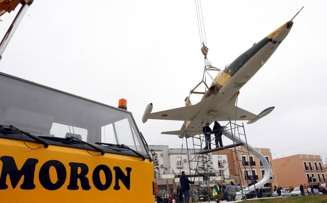 Un avión F-5, colocado por una grúa en una glorieta de Morón de la Frontera