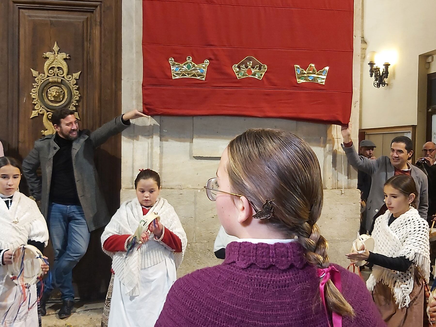 Curiosa imagen del vicealcalde y el alcalde sujetando la tela que tapa el cartel durante la actuación del Grup de Danses Carrascal