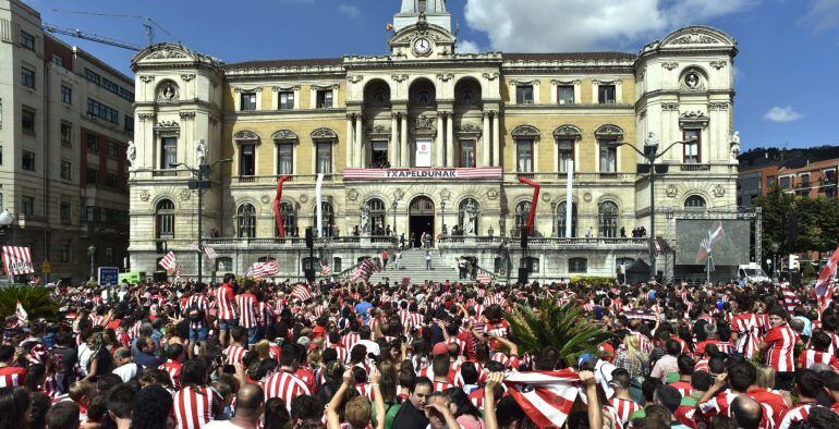 GRA179. BILBAO, 18/08/2015.- Miles de personas abarrotan la explanada del Ayuntamiento de Bilbao y sus aledaños para homenajear al Athletic Club con motivo de la Supercopa conquistada por el equipo rojiblanco ayer en el Camp Nou frente al FC Barcelona. Los jugadores han llegado a las inmediaciones de la casa consistorial, engalanada con una gran pancarta rojiblanca en su balconada en la que se leía 'Txapeldunak' (Campeones), montados en el autobús descubierto al que se han subido casi una hora antes en la Basílica de Begoña. EFE/Miguel Toña