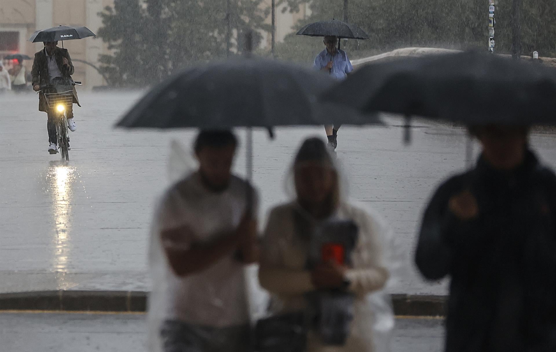 Varias personas con paraguas bajo la lluvia en València
