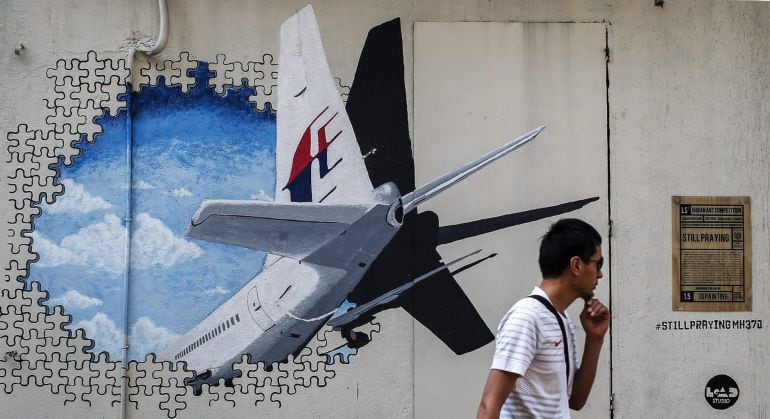 Un hombre camina junto a un mural del vuelo desaparecido de Malaysia Airlines hace un año. 