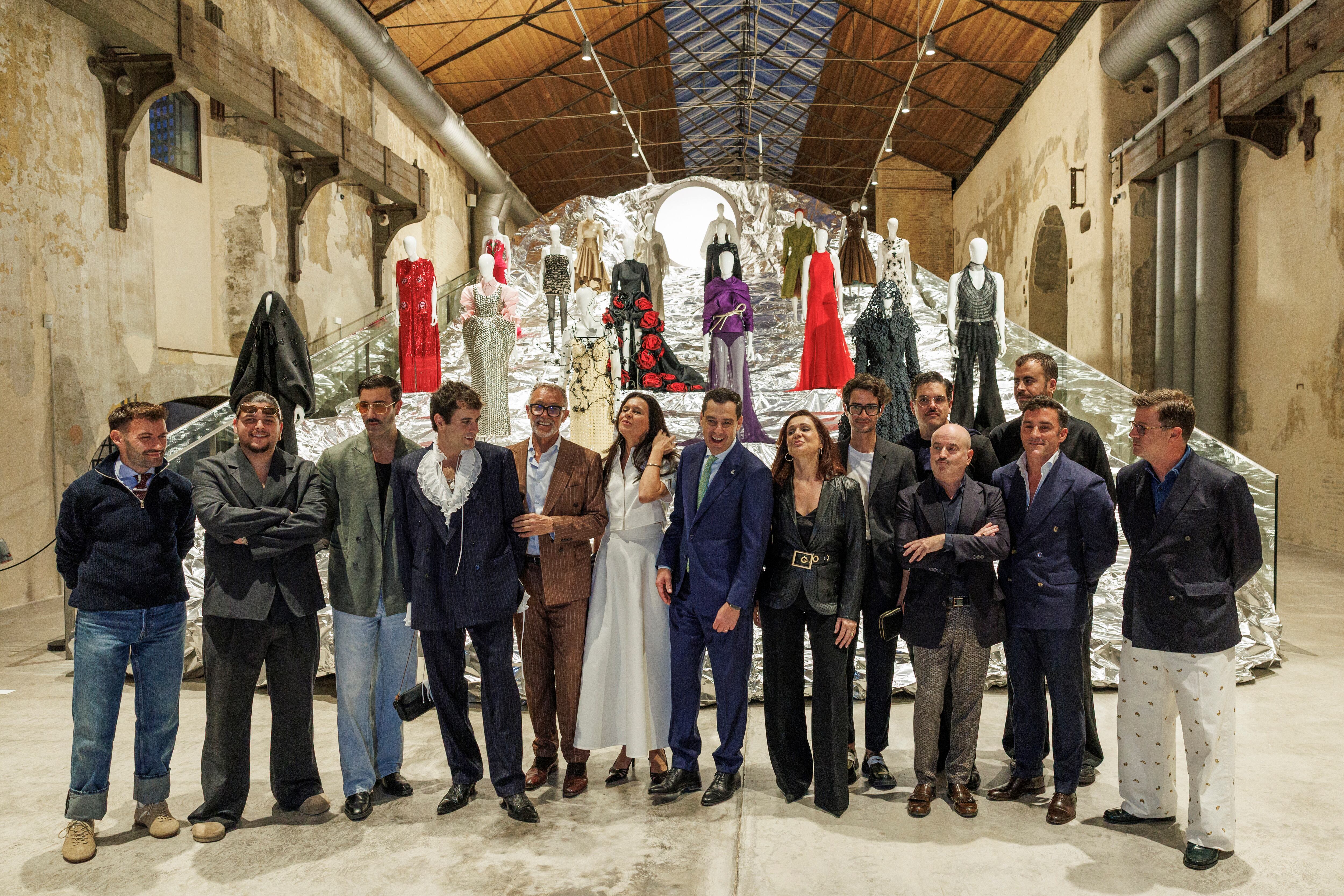 SEVILLA, 28/10/2025,- El presidente de la Junta de Andalucía, Juanma Moreno (c), posa este martes con los diseñadores andaluces que participan en la exposición ?Lux: la moda andaluza en la cultura del iglo XXI? que se desarrolla en la Fábrica de Artillería de Sevilla.. EFE/ Julio Muñoz