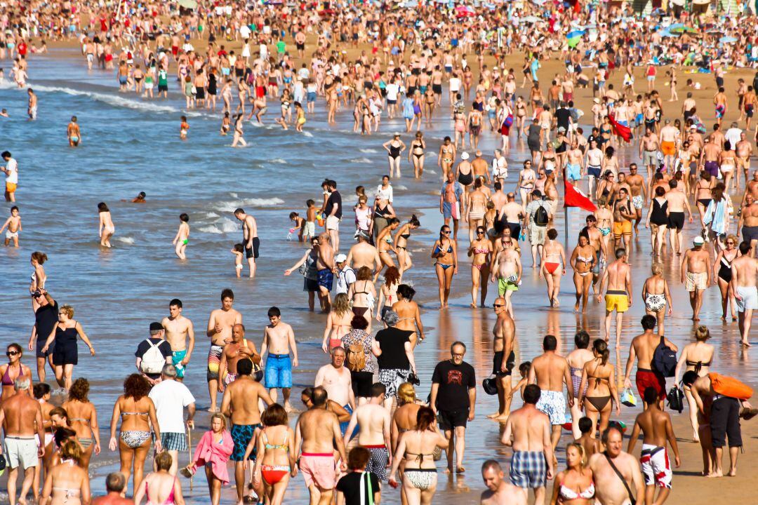 Personas paseando por la playa de San Lorenzo. 