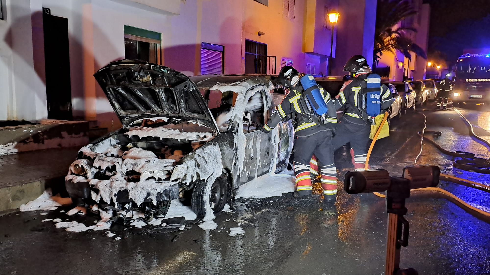 Bomberos de Lanzarote junto a un vehículo incendiado en Arrecife.