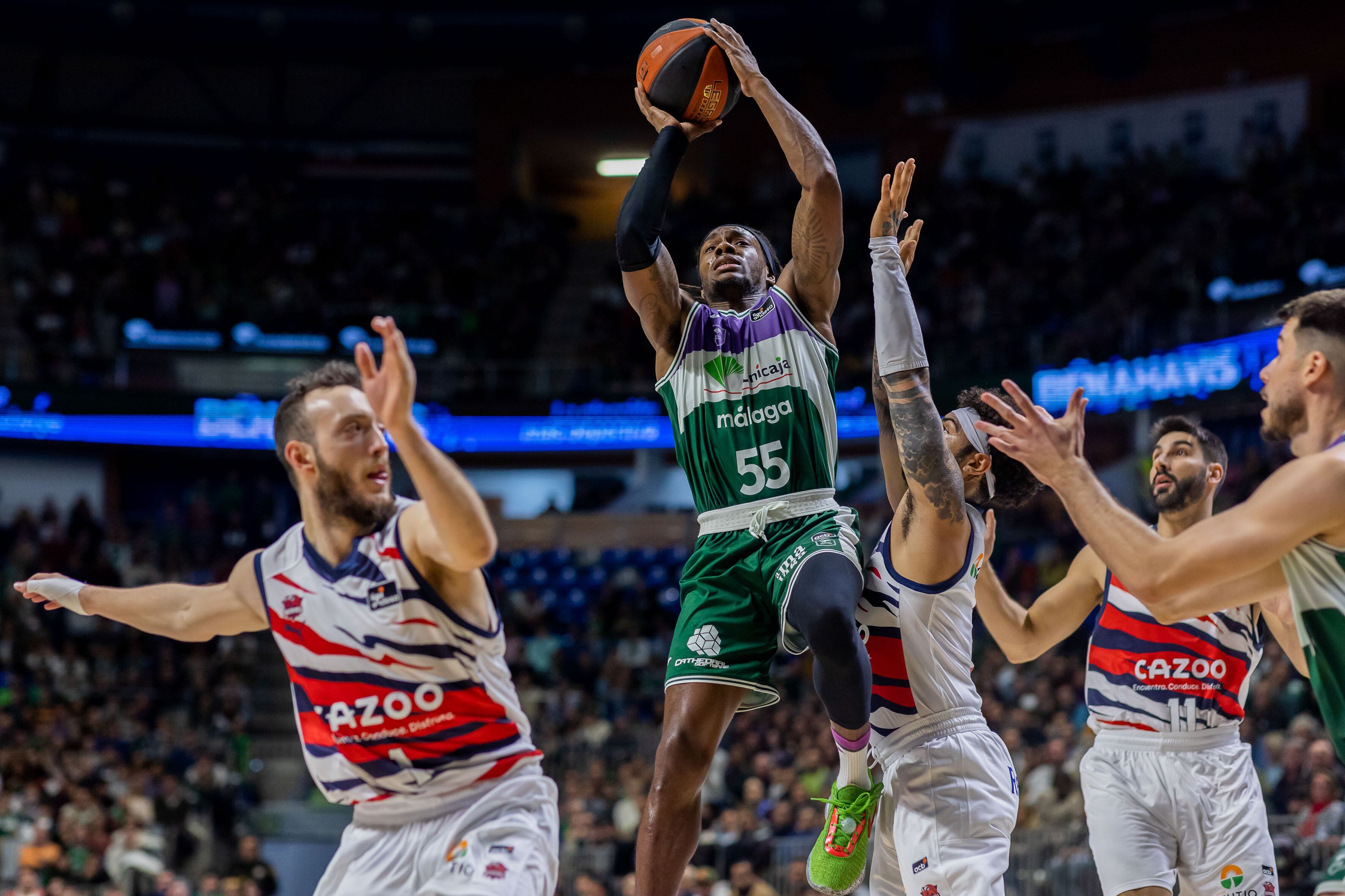 MÁLAGA, 12/02/2023.-El base estadounidense del Unicaja, Kendrick Perry (i), nza a canasta ante la defensa del base estadounidense del Cazoo Baskonia, Markus Howard 3d),durante la vigésima jornada de la Liga Endesa disputado esta noche en el Palacio de los Deportes José María Martín Carpena. EFE/Carlos Díaz