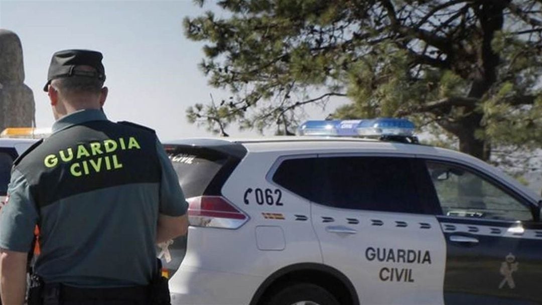 Agente de la Guardia Civil junto al coche patrulla.