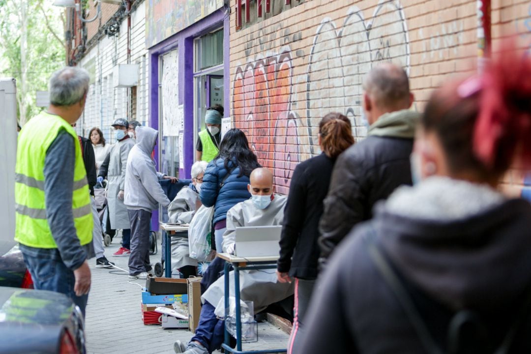 Un grupo de vecinos realizan una cola para recoger bolsas de la Asociación de Vecinos Parque Aluche durante la pandemia (archivo).