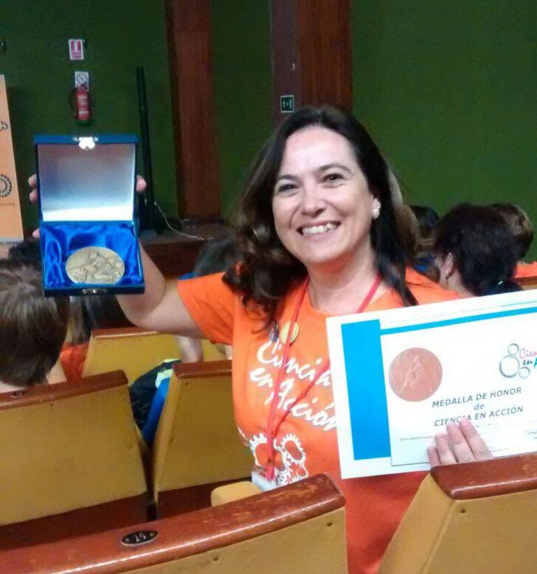 La profesora Nuria Muñoz muestra su medalla y el diploma de Ciencia en Acción.