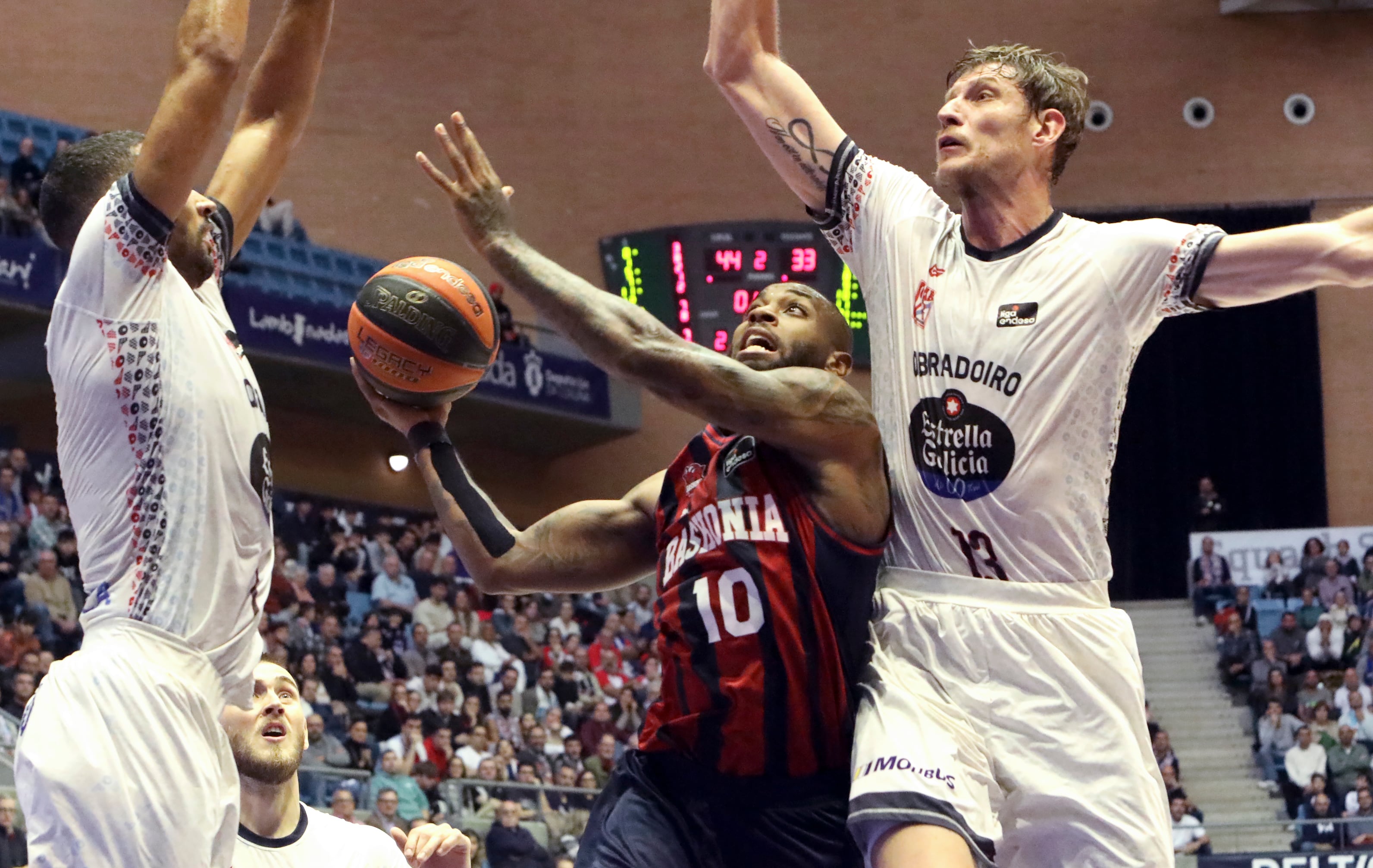 Santiago de Compostela. 12-11-23. El base búlgaro de Baskonia, Codi Miller-Mcintyre (c) busca la canasta ante los jugadores del Obradoiro, Artem Pustovyi (d) y Thomas Scrubb (i) durante el partido de la Liga Endesa que se está jugando este domingo en el Multiusos de Sar en Santiago de Copmpostela. EFE/ Xoán Rey
