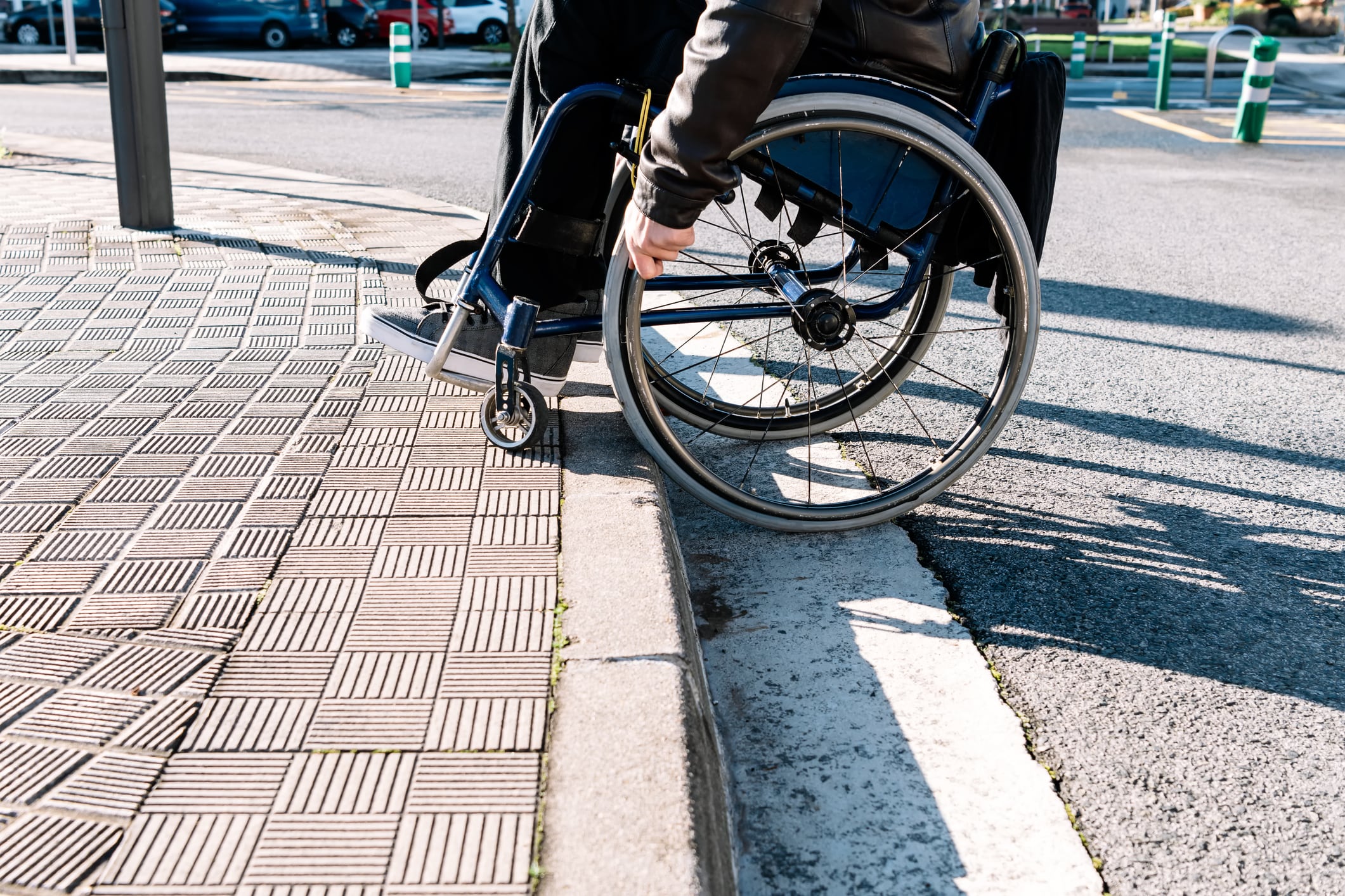 Una persona con discapacidad intenta subir el bordillo de una calle que no está adaptada para movilidad reducida.