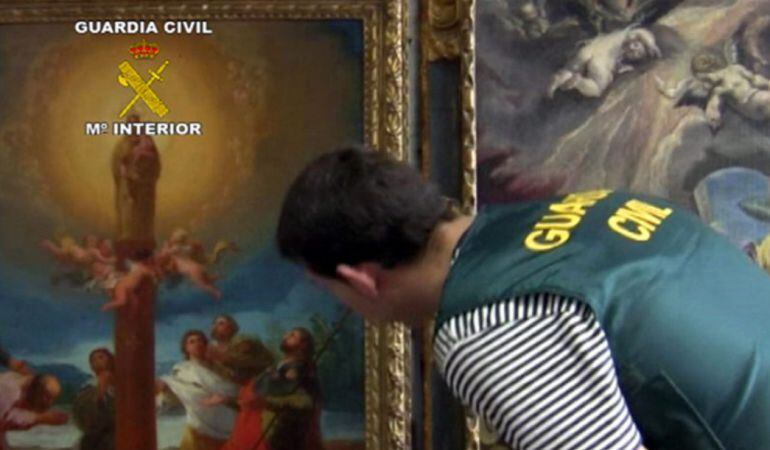 Un agent de la Guàrdia Civil inspecciona el quadre de Goya 'La Aparición de la Virgen del Pilar' al costat de 'La Anunciación' del Greco