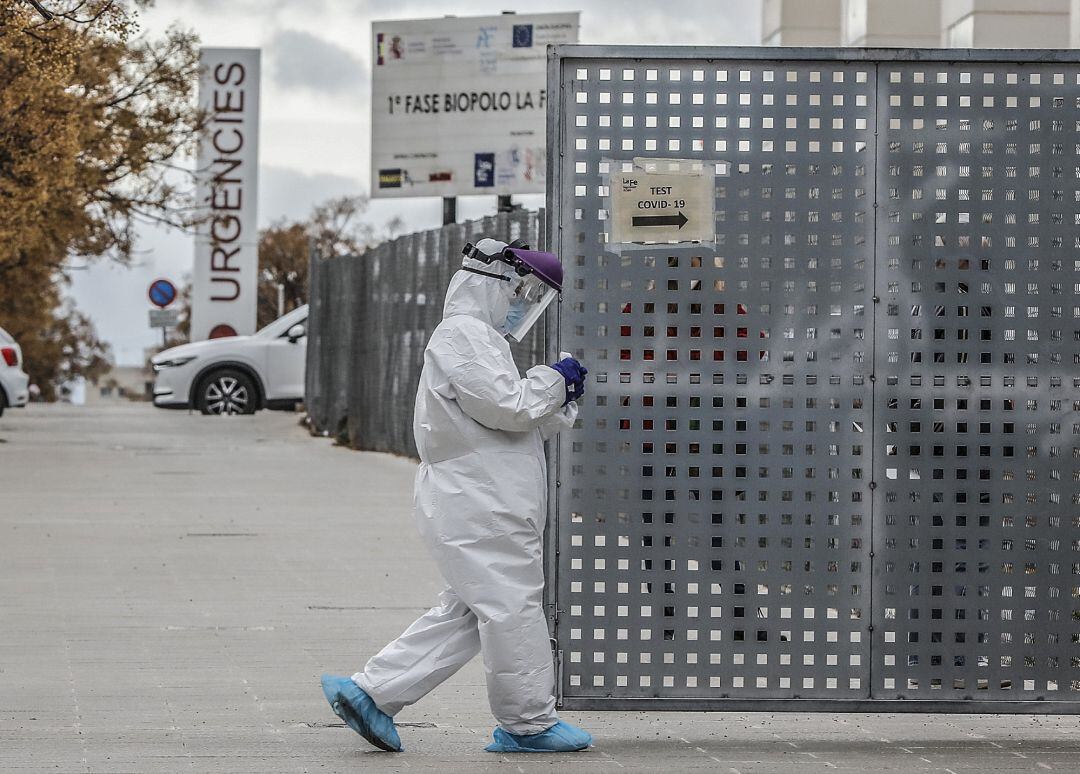 Un sanitario a los alrededores de la fila de vehículos para realizarse una prueba PCR de detección del coronavirus a las puertas del Hospital de Campaña próximo al de La Fe, en València