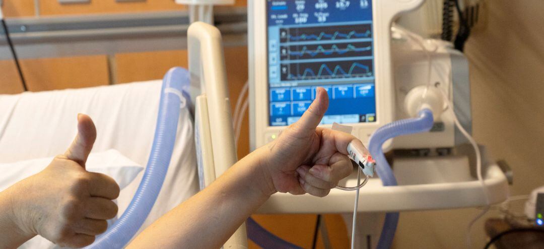 Una enferma de coronavirus saluda con la mano mientras está en el hospital.