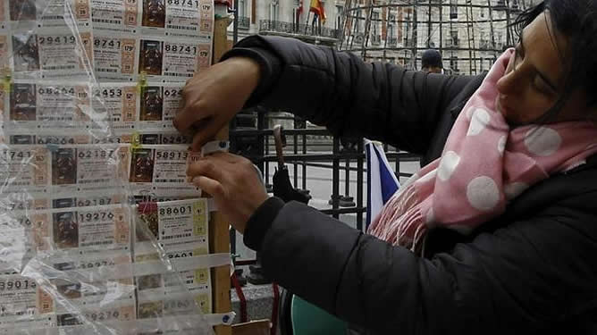 Una mujer coloca un décimo acabado en 13 en la Puerta del Sol de Madrid