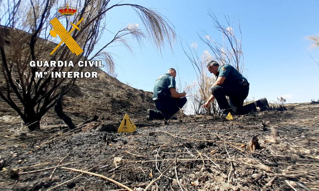 Dos guardias civiles comprueban una zona afectada por uno de los incendios de Hinojares.