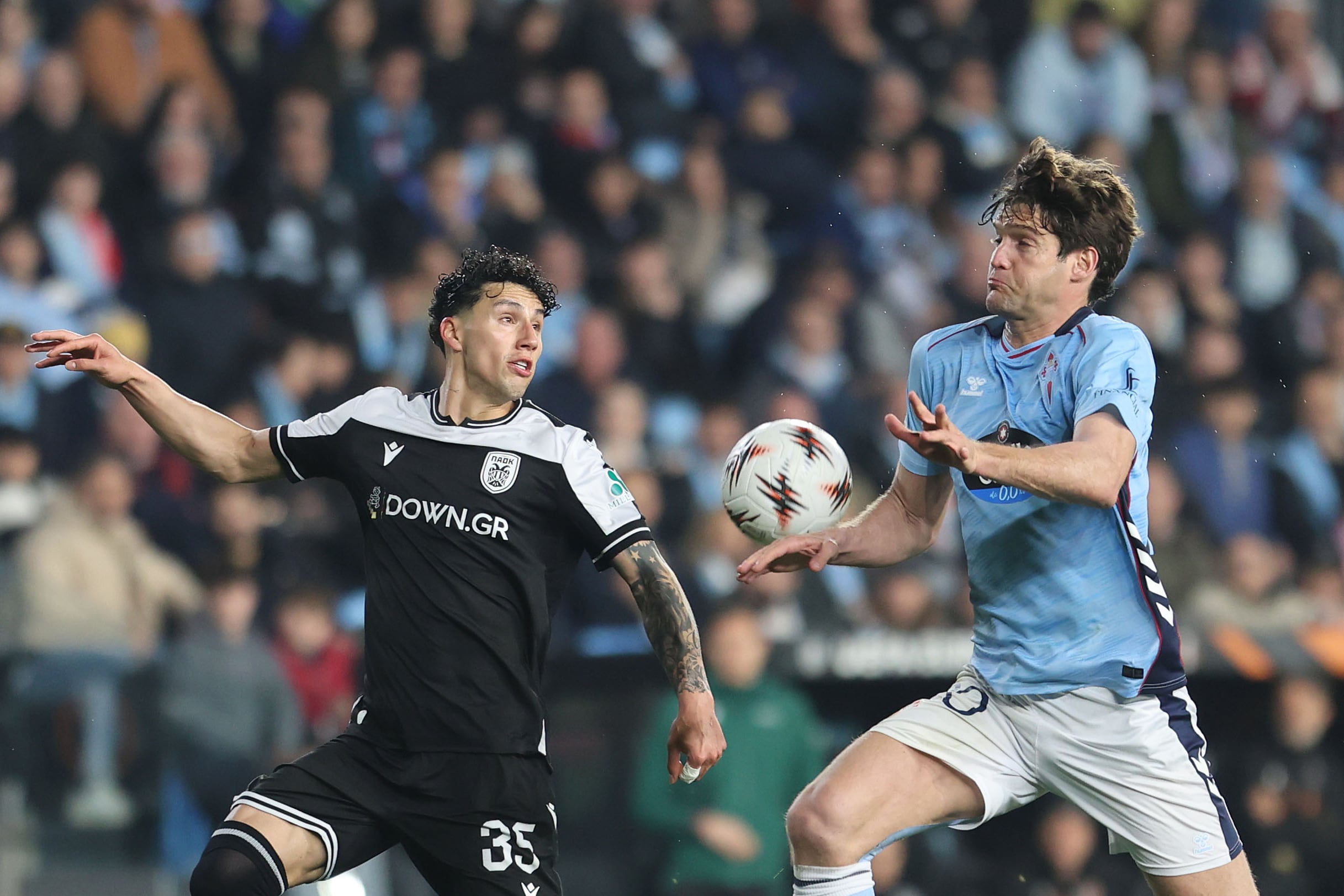 VIGO (PONTEVEDRA), 26/02/2026.- El defensa del Celta Marcos Alonso (d) pelea un balón con Jorge Sánchez, del PAOK, durante el partido de vuelta de los deiciseisavos de final de la Liga Europa que Celta de Vigo y PAOK FC disputan este jueves en el estadio de Balaídos. EFE/Salvador Sas