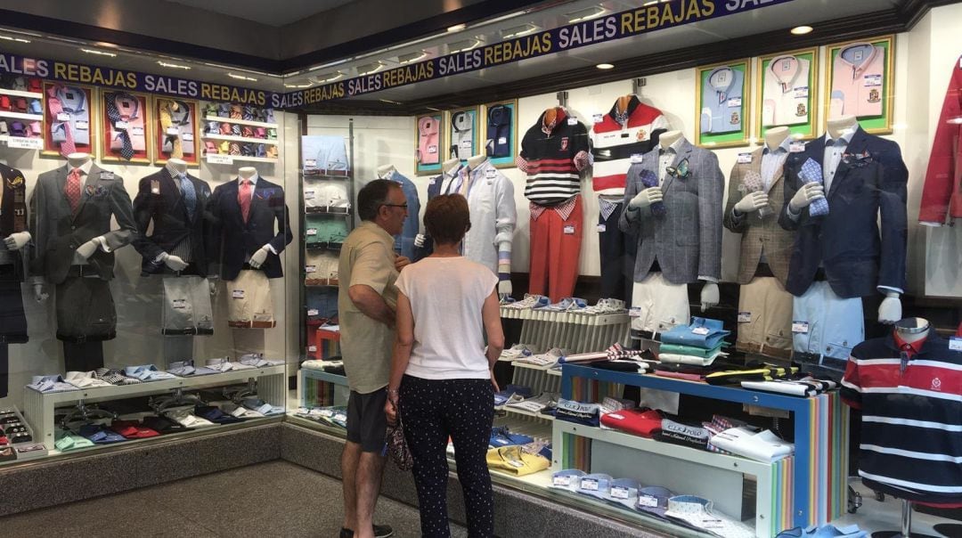 Dos personas contemplan un escaparate de una tienda en rebajas.