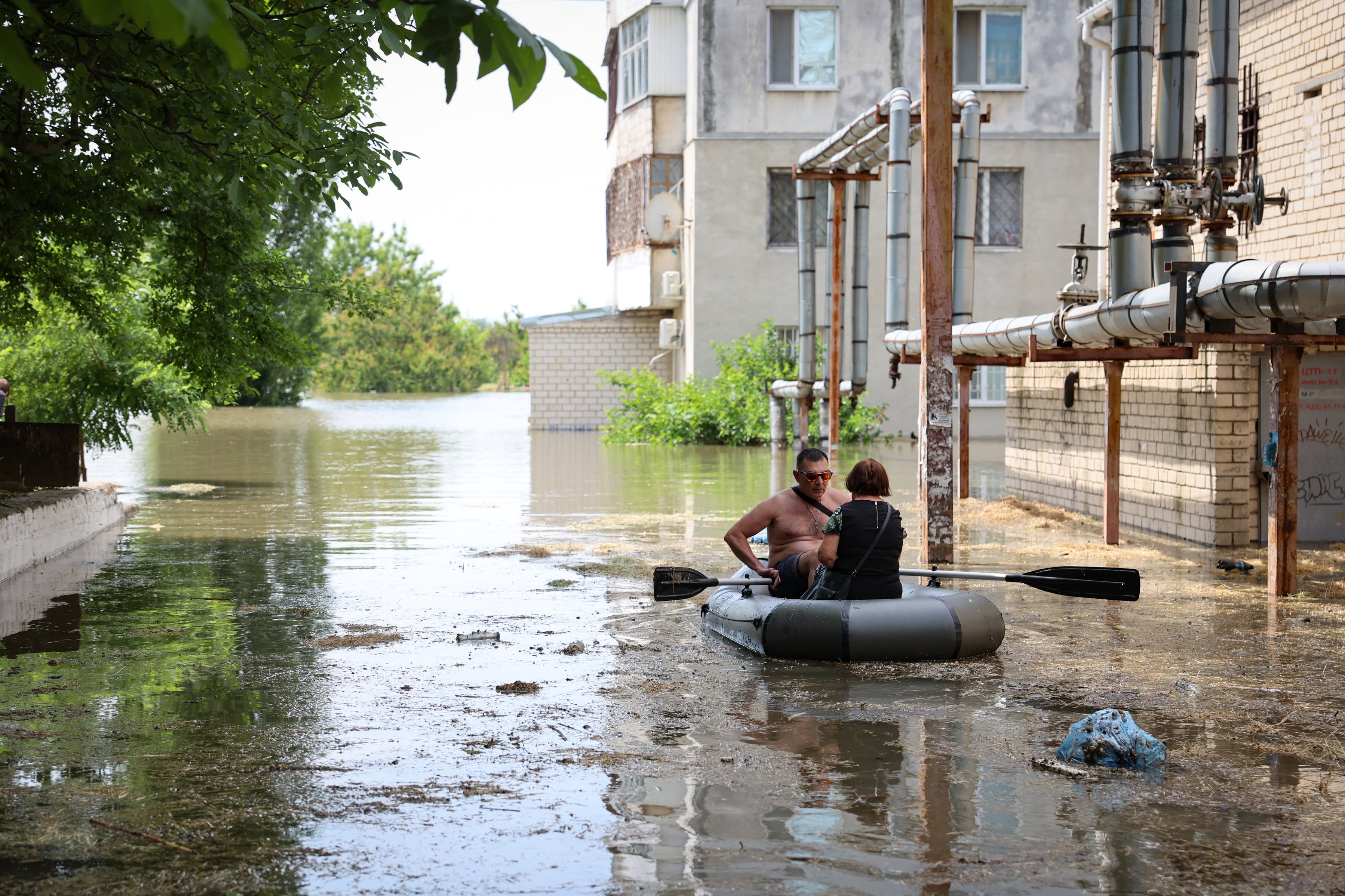 Un hombre y una mujer recorren en un bote hinchable una calle de Jersón después de la destrucción de la presa de Kajovka