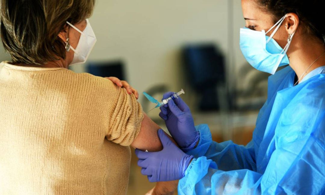 Personal sanitario administra la vacuna a una mujer.