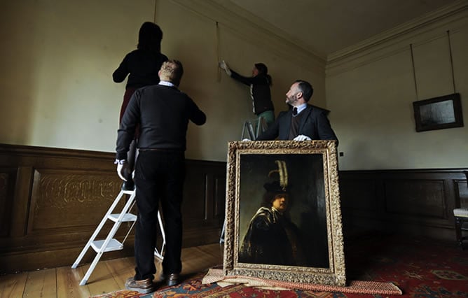 Fotografía facilitada que muestra a trabajadores del Buckland Abbey colgando un autorretrato de Rembrandt descubierto recientemente en Devon (Reino Unido)