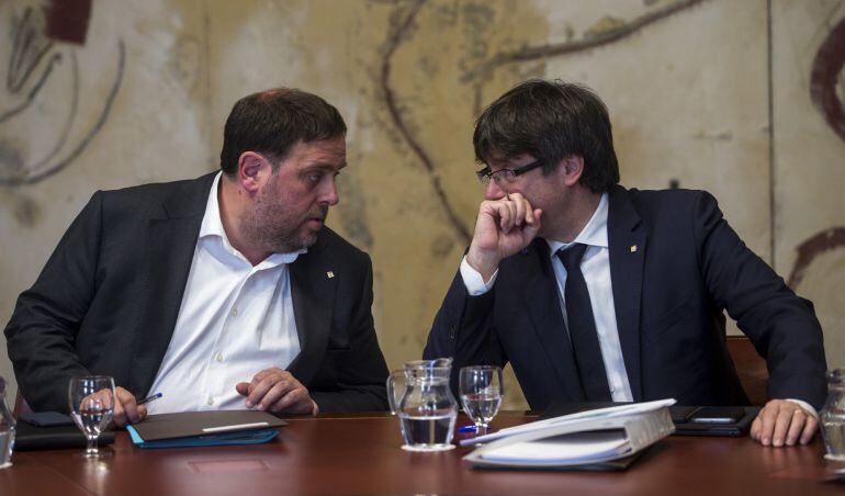 El presidente de la Generalitat, Carles Puigdemont (d) habla con el vicepresidente del Govern y conseller de Economía ,Oriol Junqueras, durante la reunión semanal del Govern