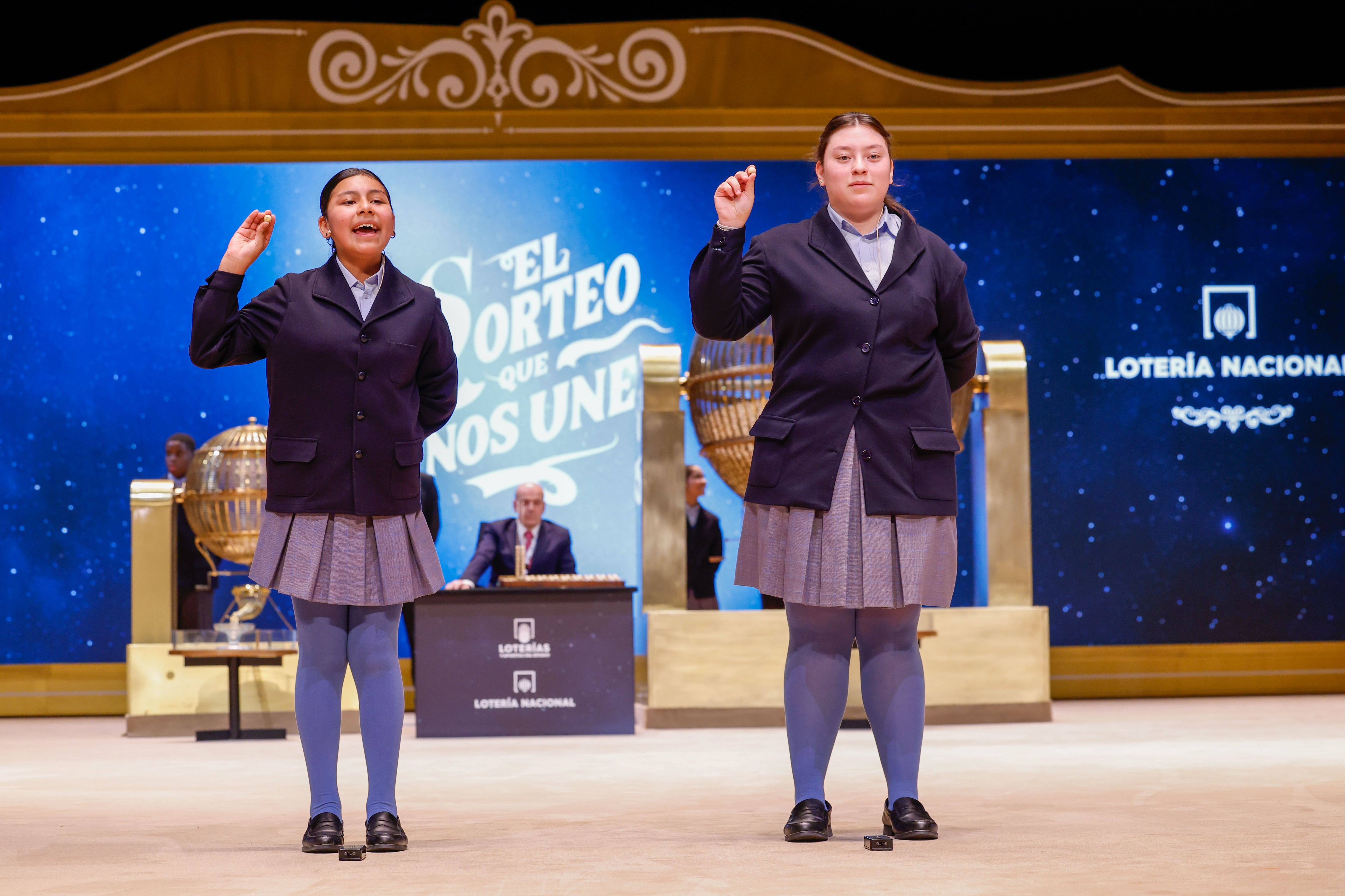 Las niñas de la Residencia San Ildefonso de Madrid Yadira Quinde Mendoza (i) y Kiara Román Benítez (d) muestran el número 45.225, uno de los quintos premios, durante el sorteo de la Lotería de Navidad que se celebra este domingo en el Teatro Real, en Madrid. EFE/Javier Lizón