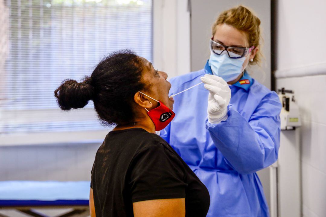 Una trabajadora sanitaria protegida realiza un test a una mujer.