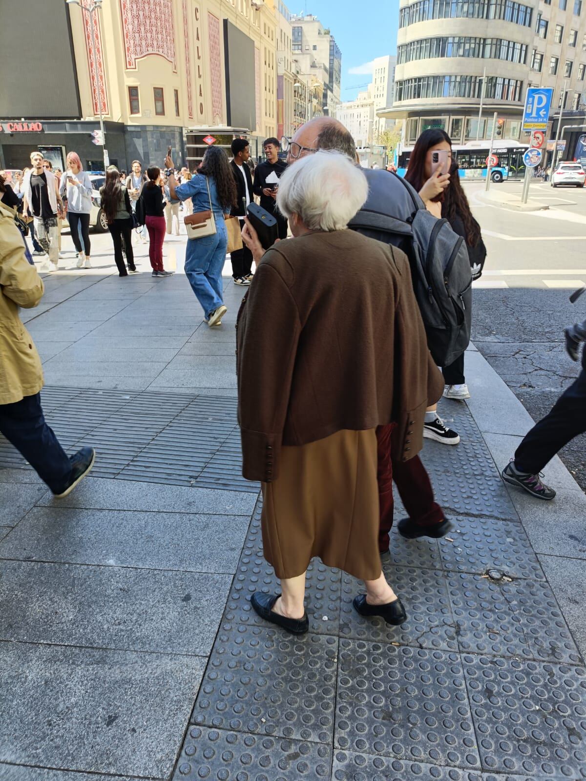 Una mujer mayor utilizando un transistor para seguir la actualidad sobre el apagón en la plaza del Callao de Madrid.