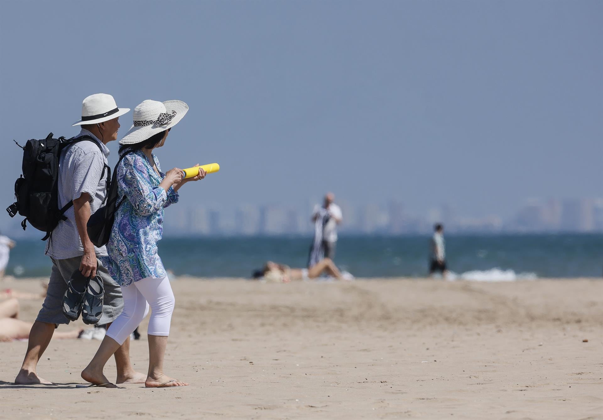 Varias personas caminan por la playa de la Malvarrosa