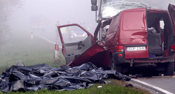 Los cadáveres de las víctimas cubiertas con mantas junto al lugar donde se produjo el choque frontal de un camión y una furgoneta en Nowe Miasto, al sur de Varsovia (Polonia), lo que causó la muerte de 18 personas