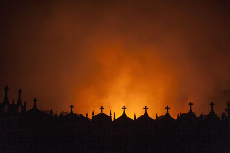 Catorce incendios continúan pendientes de extinción en Galicia. En la imagen, cementerio del pueblo de Espiño (Oímbra) a donde se ha acercado el incendio forestal declarado a última hora de la tarde de ayer en Cualedro, que permanece activo y cuyo fuego s