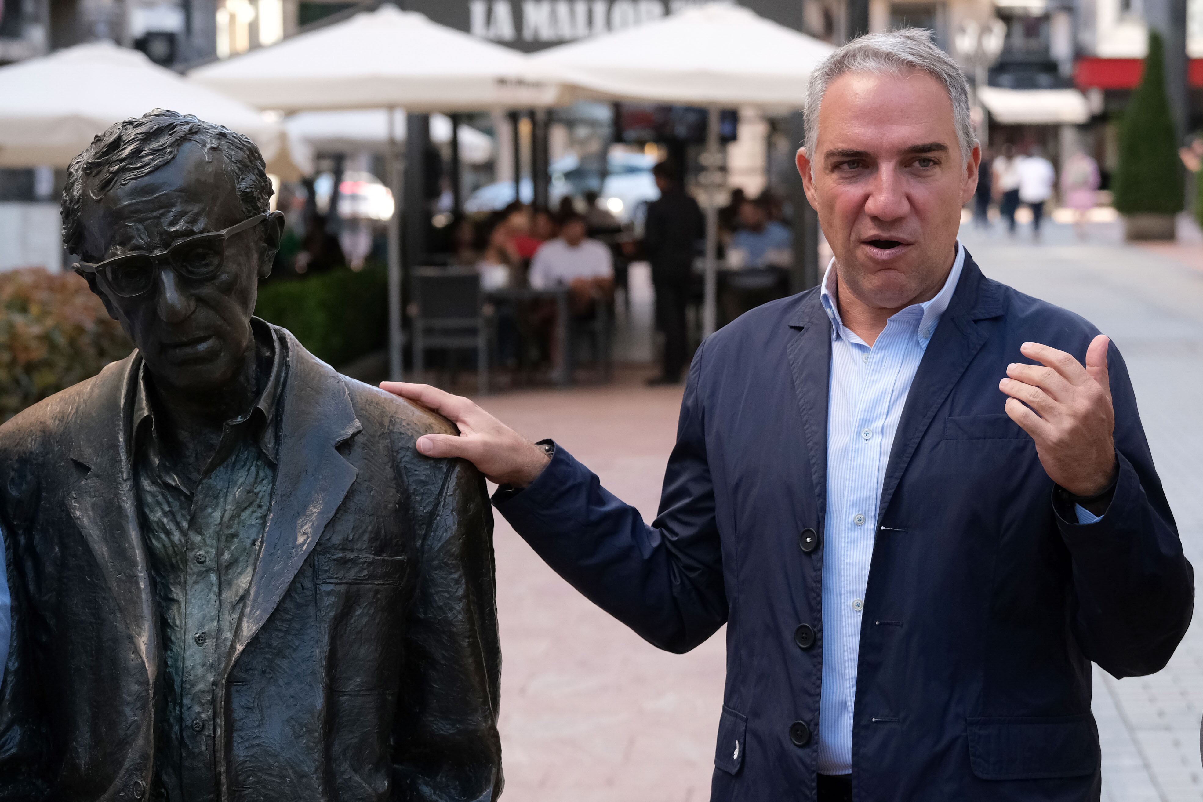 El coordinador general del PP, Elías Bendodo(2d), atiende a los medios y posa junto a la estatua de Woody Allen en Oviedo este domingo.