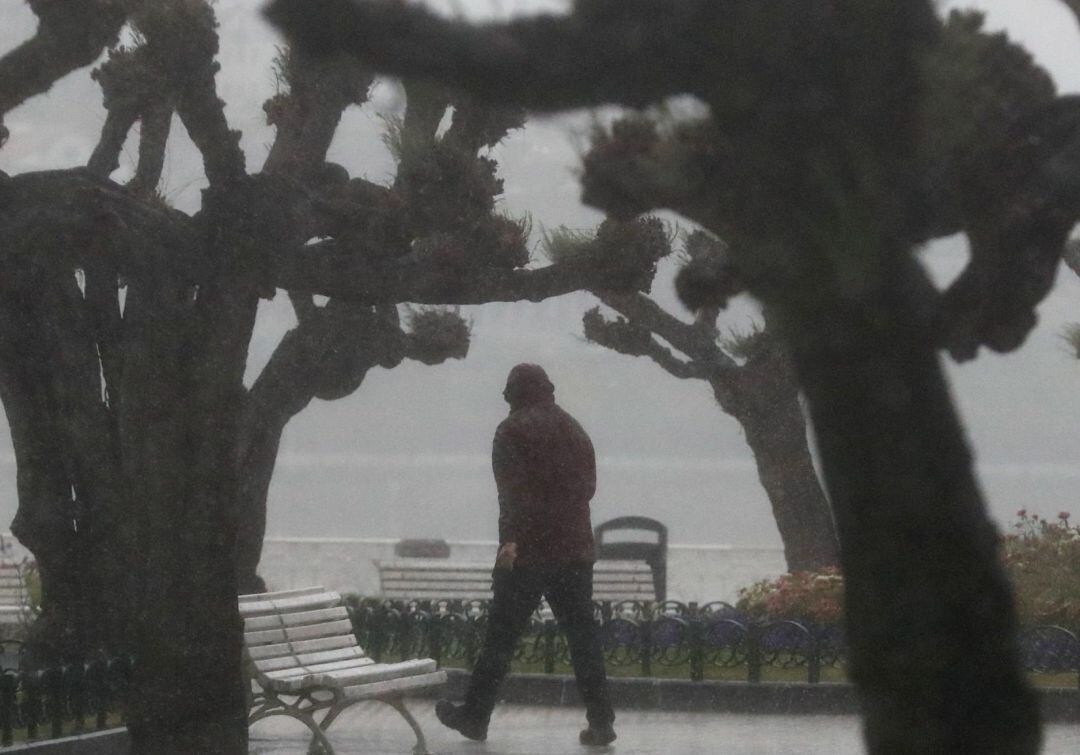 Un hombre camina por el paseo de la Concha de San Sebastián durante una fuerte galerna que ha provocado intensas lluvias y bajada de las temperaturas.