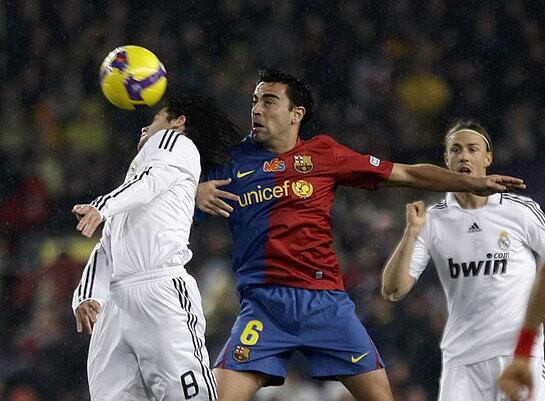 Xavi y Gago pelean un balón ante la atenta mirada de Guti