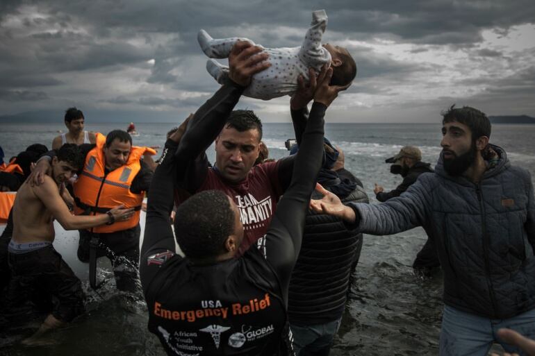 Voluntarios ayudan a varios refugiados a desembarcar de una lancha en Lesbos, Grecia.