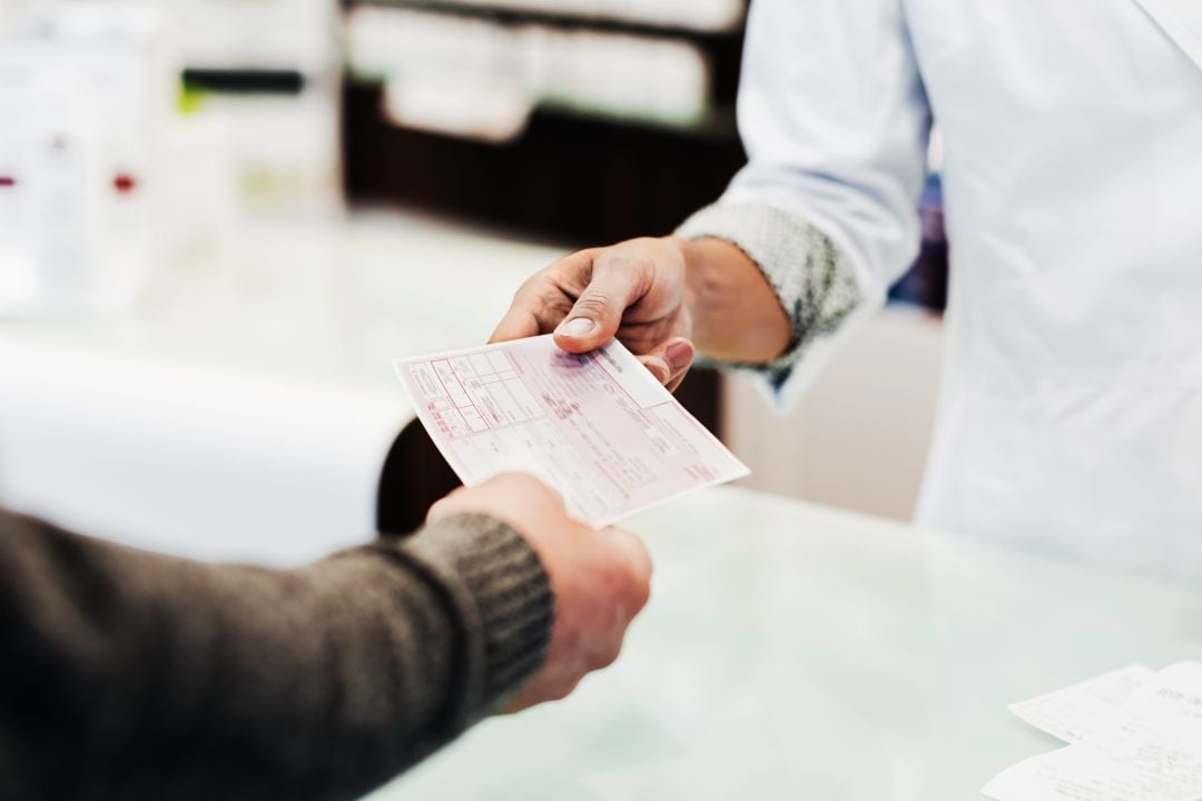 Un hombre entrega una receta en la farmacia.