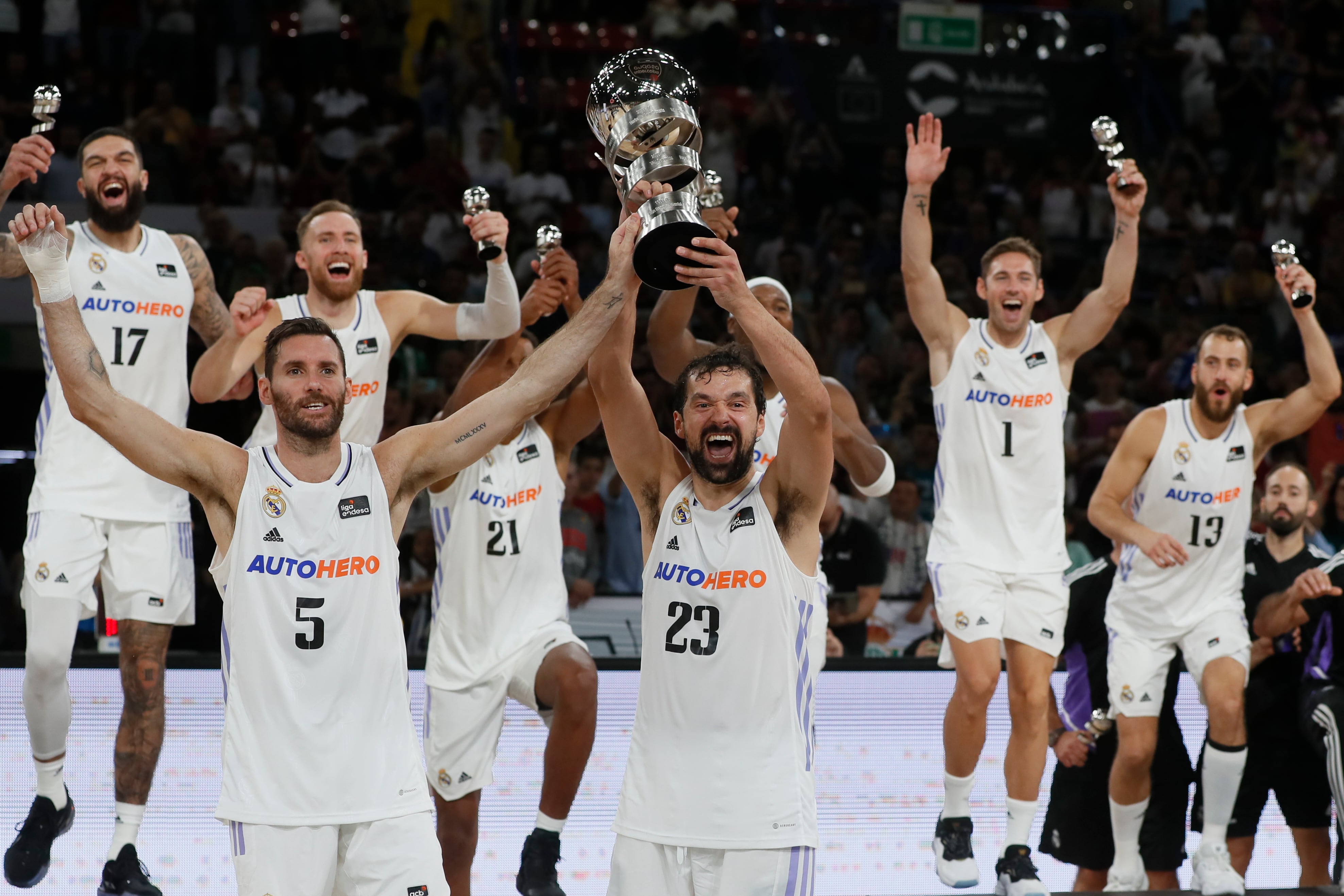 SEVILLA, 25/09/2022.- Los jugadores del Real Madrid Sergio Llull (3-d) y Rudy Fernández (2-i) levantan el trofeo tras su victoria ante el Barcelona, al término de la final de la Supercopa de baloncesto disputada este domingo en el pabellón de San Pablo, en Sevilla. EFE/Jose Manuel Vidal
