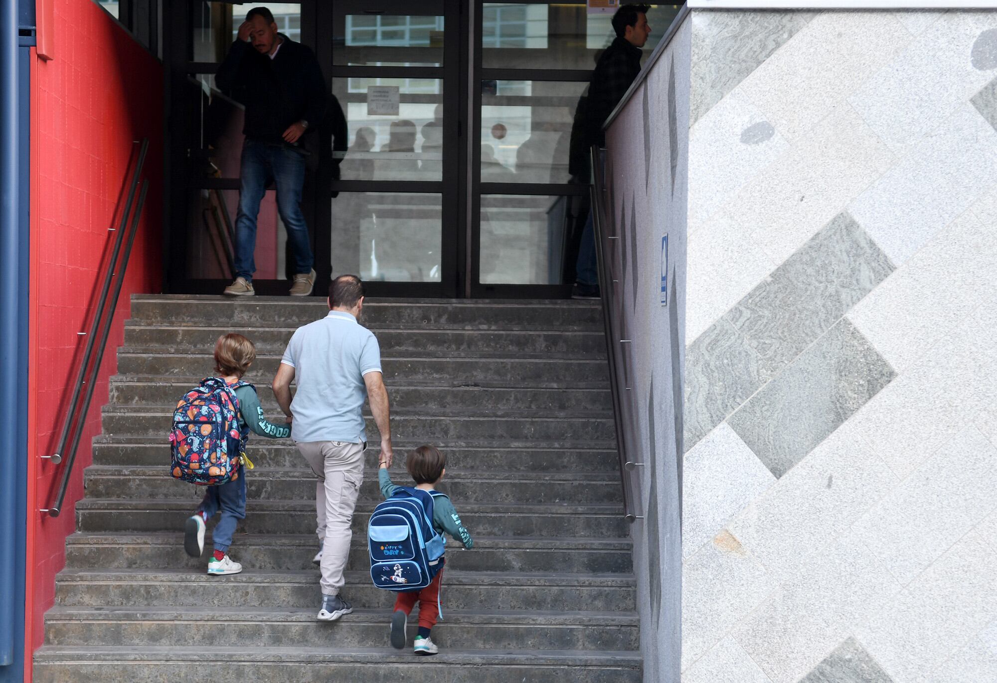 Un pare acompanya els seus fills en el primer dia de curs escolar.