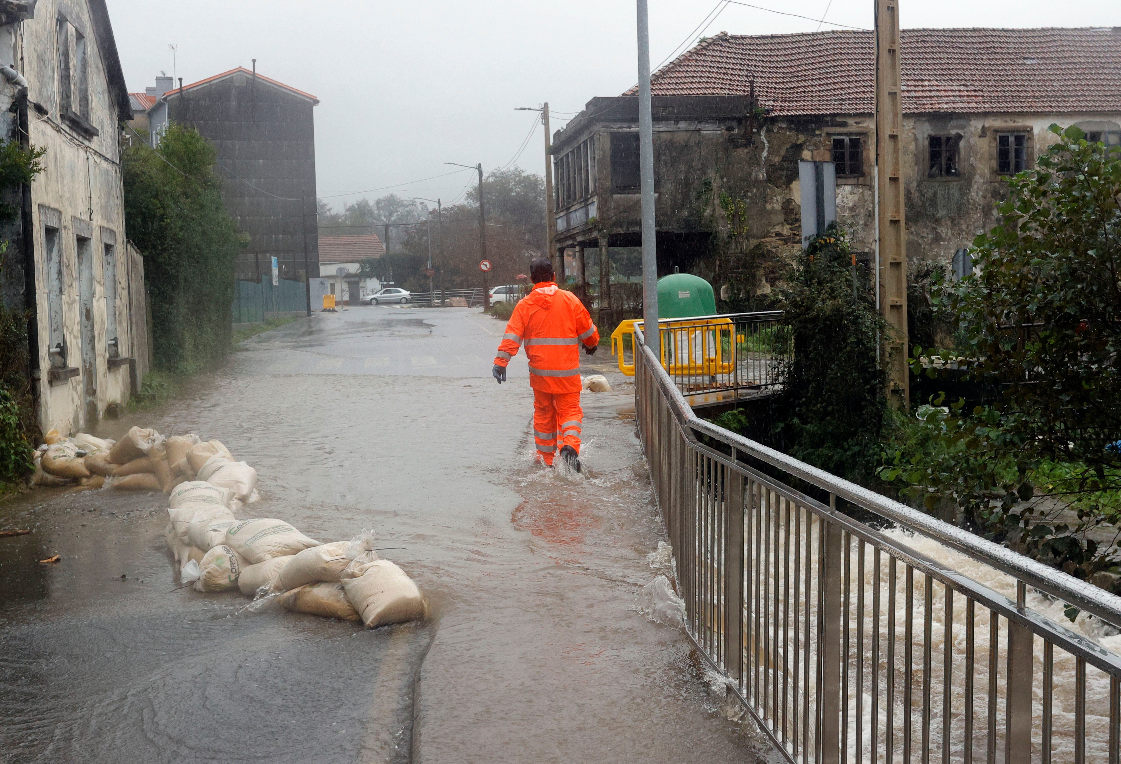 FENE (A CORUÑA), 14/11/2023.- Un hombre pasa por una calle anegada tras el desbordamiento del río Cádavo a causa de las últimas lluvias registradas en Fene (A Coruña). EFE/ Kiko Delgado
