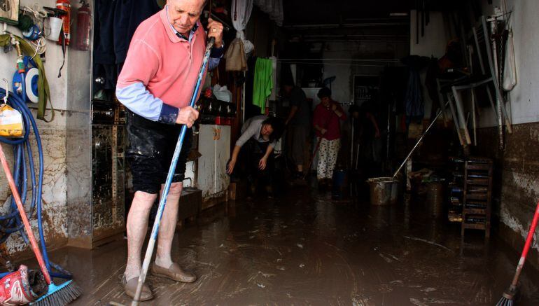 Un veí d'Agramunt escombra l'aigua i el fang cap a fora de casa seva. Imatge del 3 de novembre de 2015.