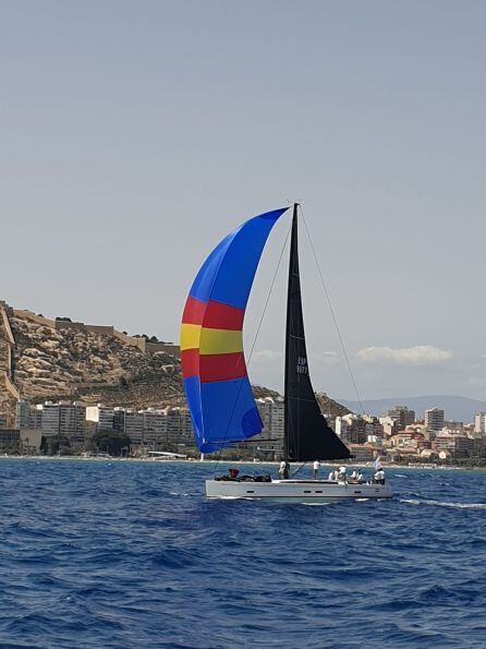 Una de las embarcaciones de la regata con la ciudad y el castillo al fondo