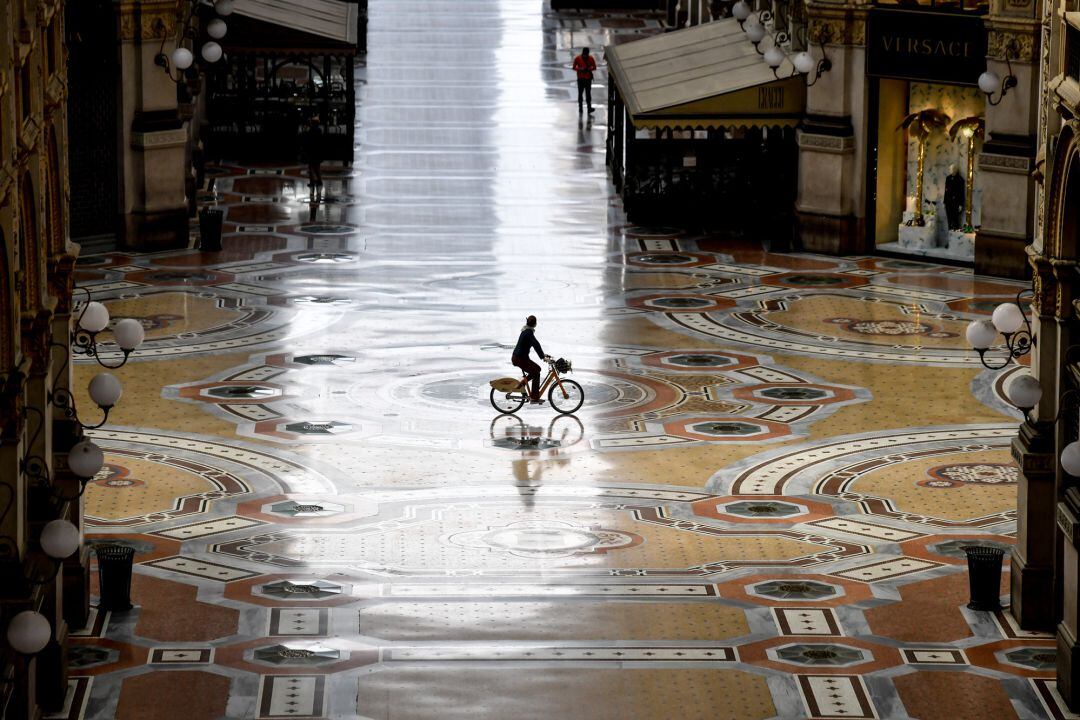 Un hombre en bicicleta en la desierta Galleria Vittorio Emanuele de Milán 