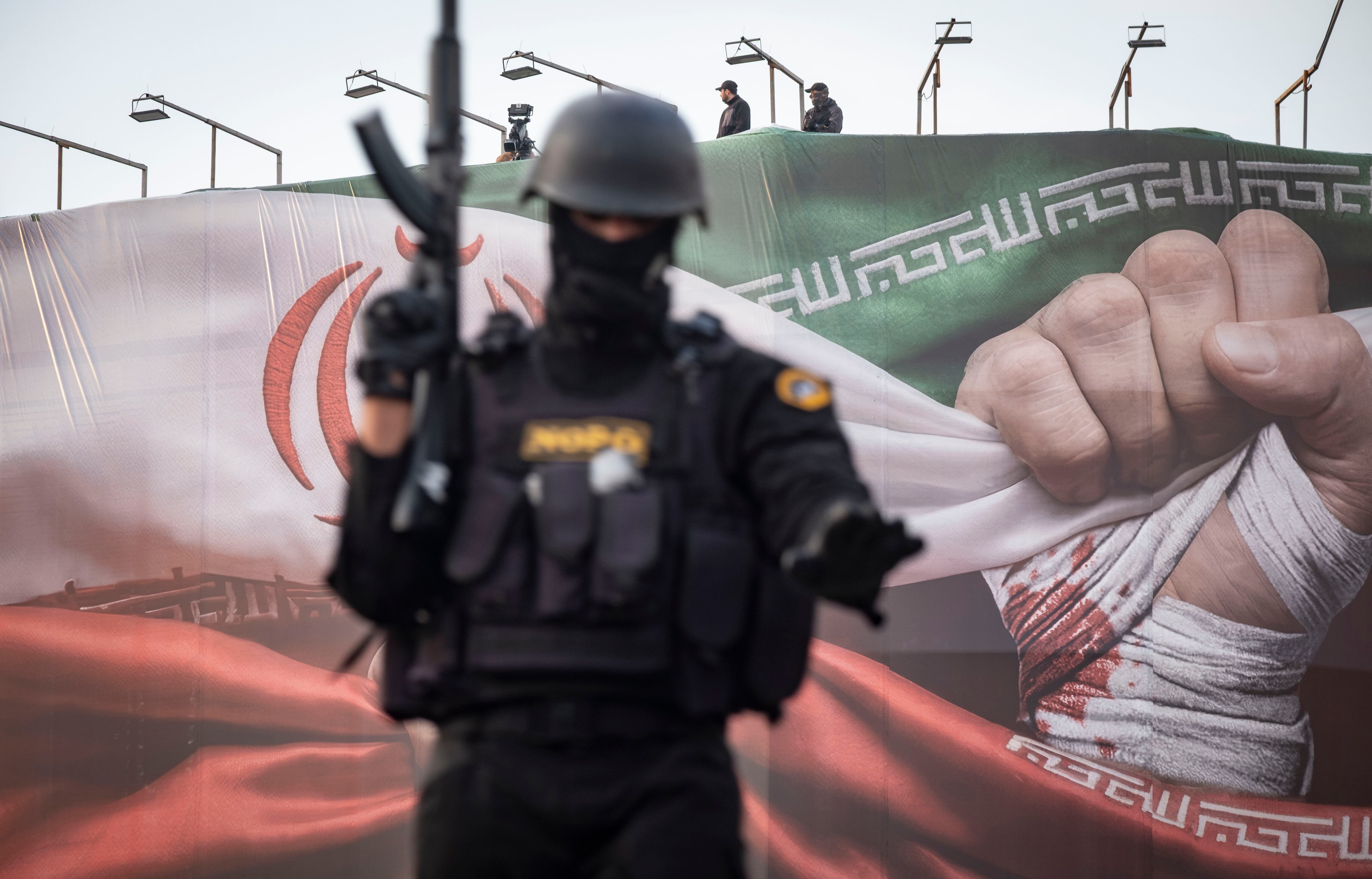 Miembros armados de las fuerzas especiales de la policía de Irán vigilan una zona mientras se encuentran en un vehículo militar blindado bajo una bandera del país durante una manifestación progubernamental en el centro de Teherán