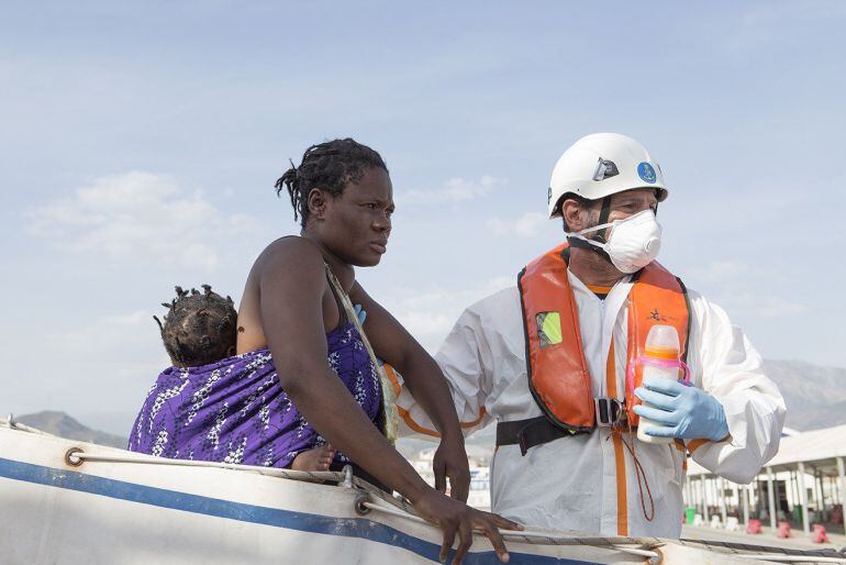 Una mujer con su bebé es ayudada a bajar en el puerto de Motril (Granada) donde han sido trasladados después de que Salvamento Marítimo haya rescatado este martes a un total de 34 personas cuando viajaban en una patera a 7,5 millas al sur de la isla de Al
