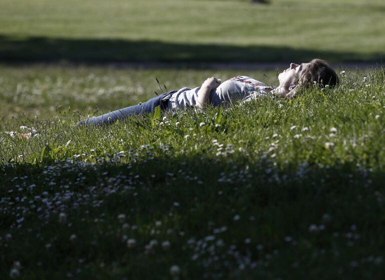 Una mujer disfruta de una tarde soleada y con temperaturas de casi 30 grados en el parque Yamaguchi de Pamplona