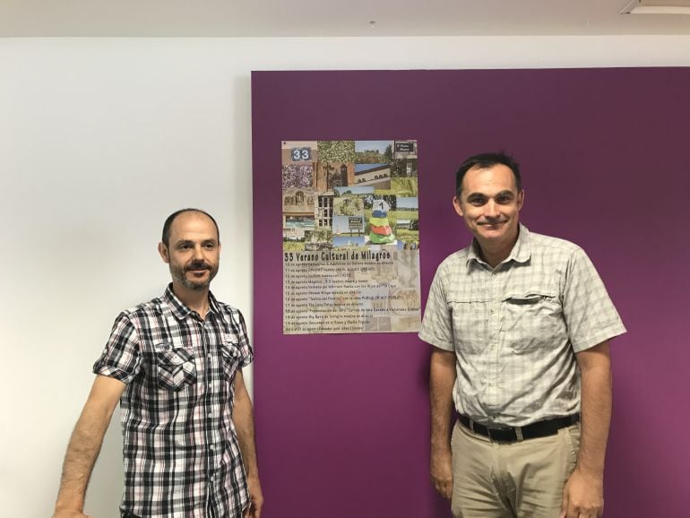 El vicepresidente de la asociación Milcampos, Diego Pérez, y su presidente, David Abad, flanquean el cartel de la 33 edición del Verano Cultural de Milagros, obra de Carlos Gómez