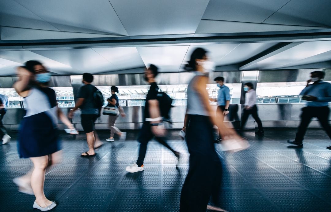 Varias personas caminan por la calle con su respectiva mascarilla puesta.